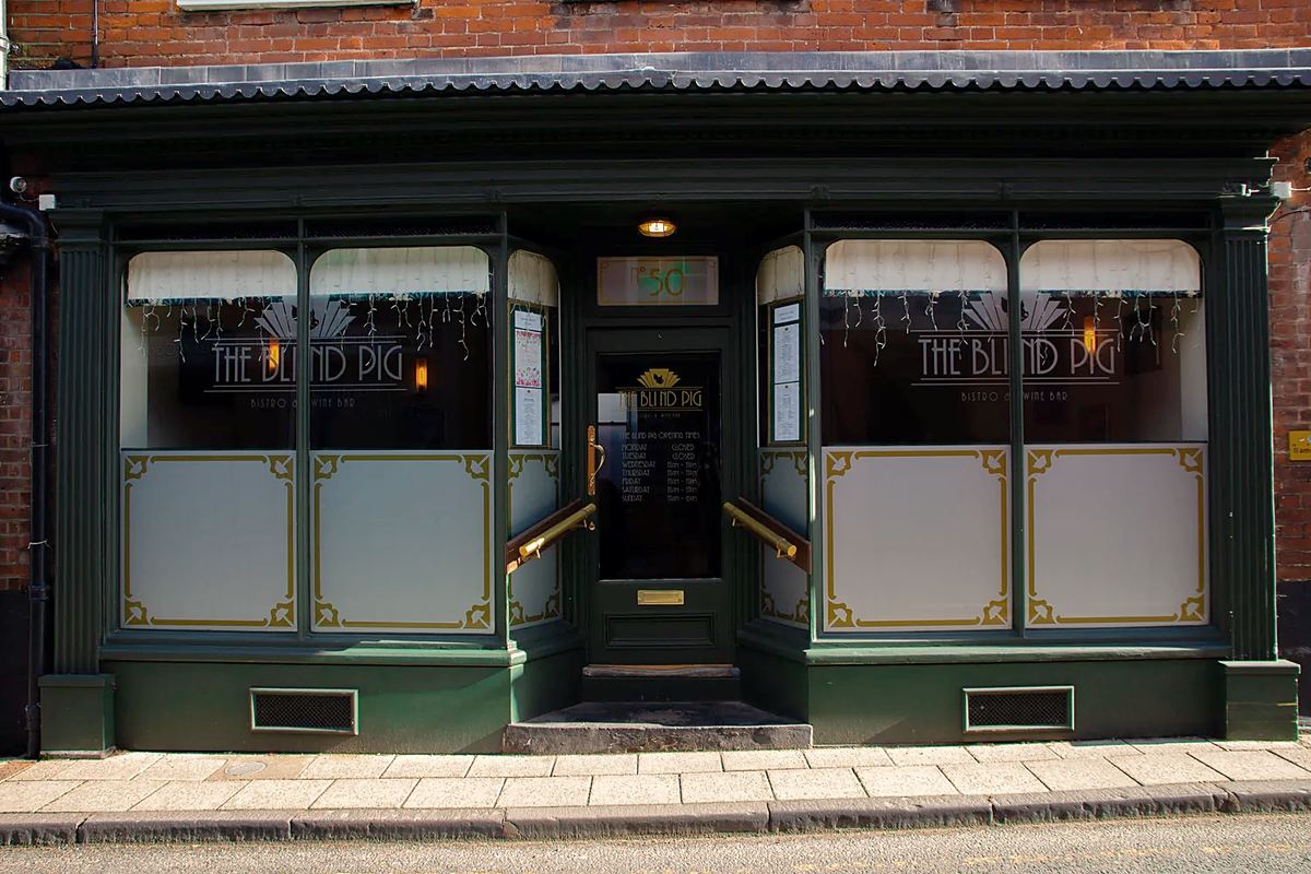 The Blind Pig's dark green shopfront: the name on the glass, frosted panels edged in gold below