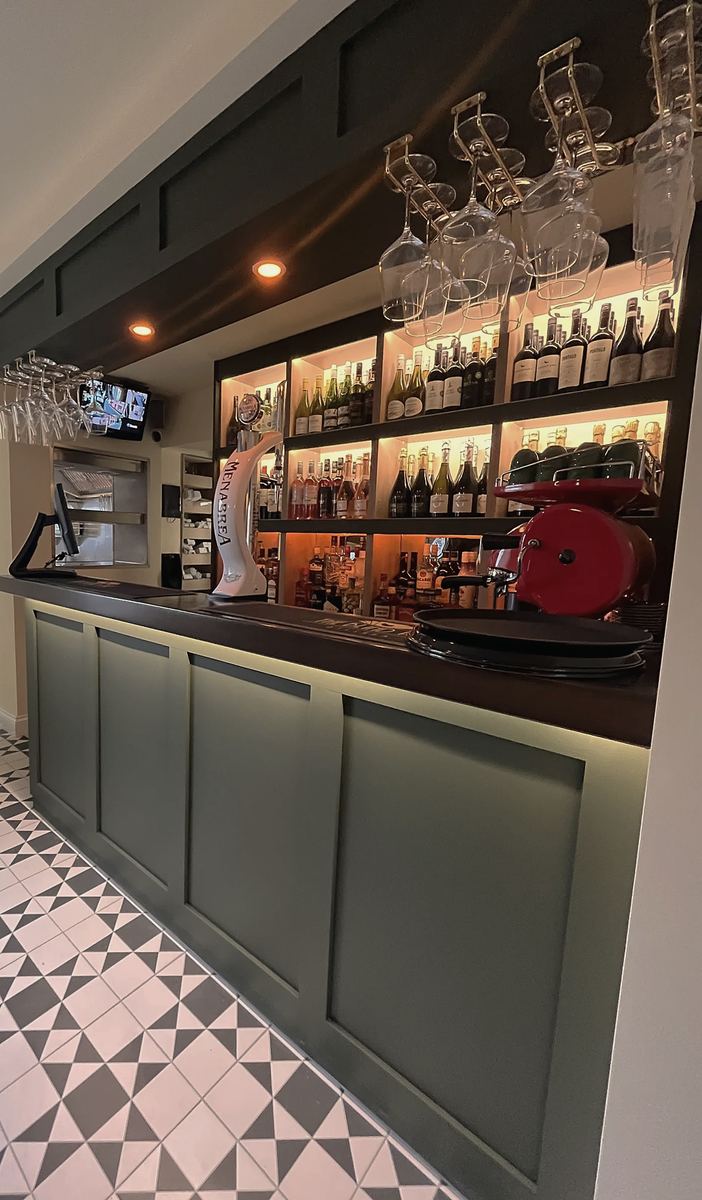 The bar inside, with dark green panelling, shelves of bottles and a black-and-white tiled floor