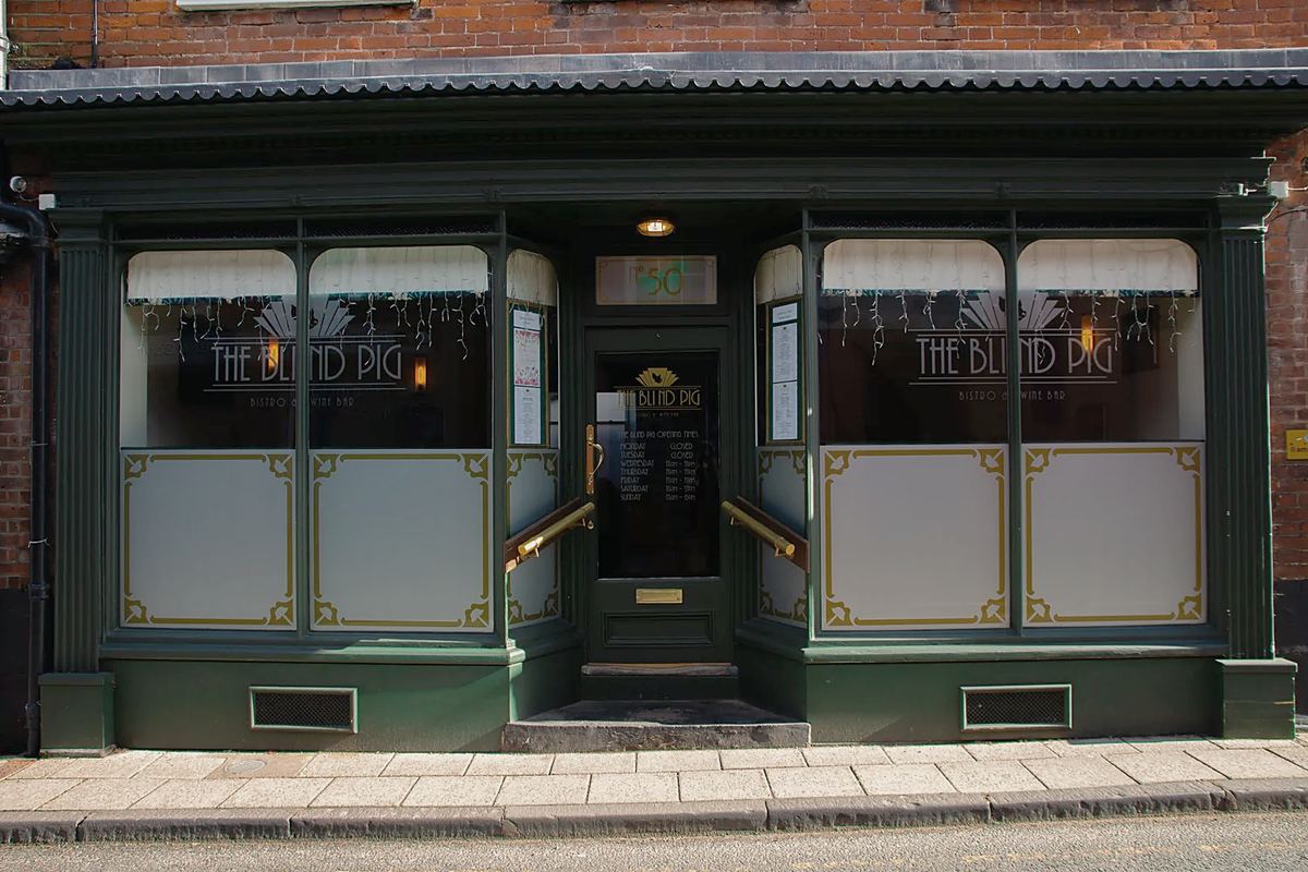 The Blind Pig's dark green shopfront: the name on the glass, frosted panels edged in gold below