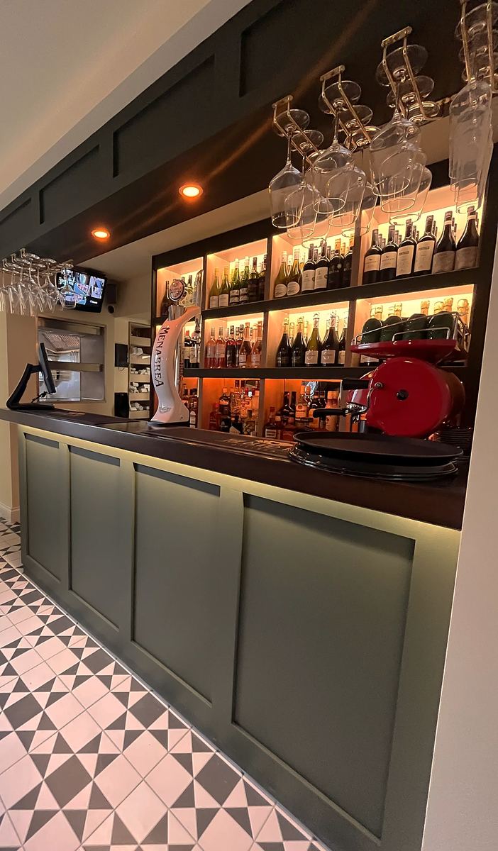 The bar inside, with dark green panelling, shelves of bottles and a black-and-white tiled floor