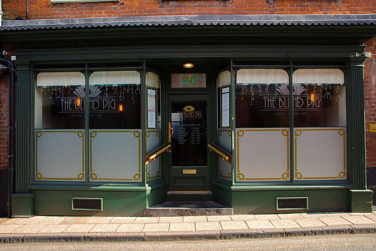 The Blind Pig's dark green shopfront: the name on the glass, frosted panels edged in gold below